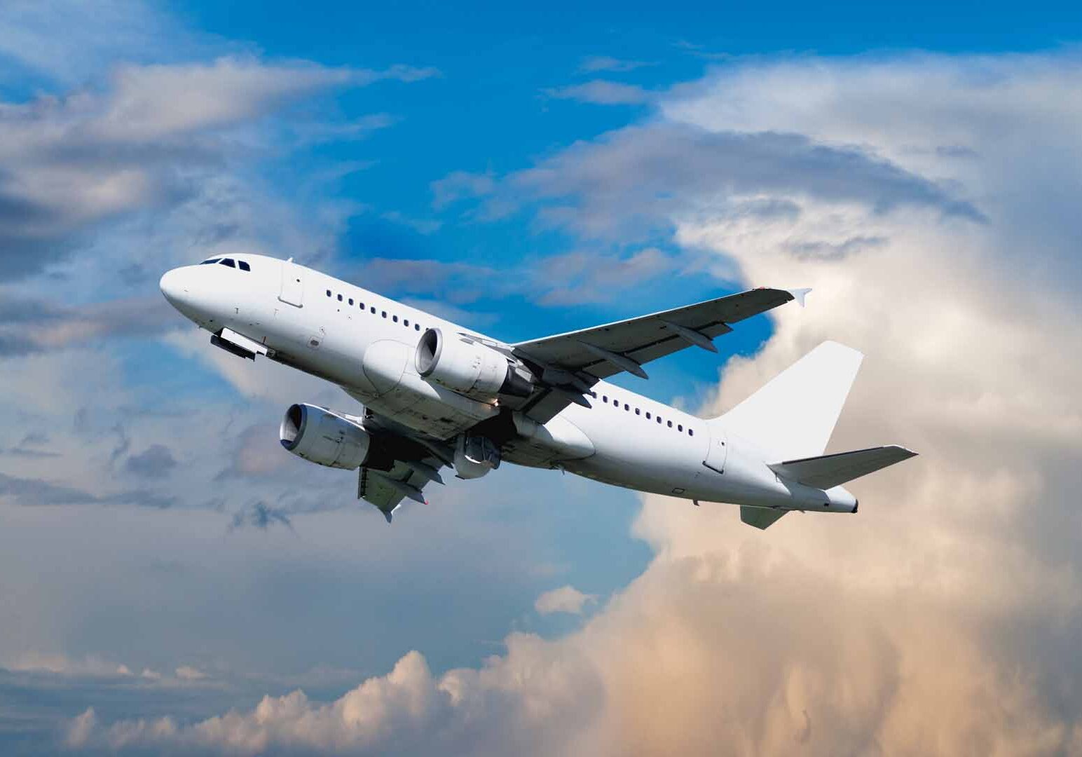 Airplane flying in the sky - travel background with flying airplane with blank livery